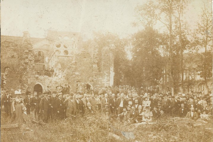 Foto van Dr. P.J.H. Cuypers met gezamenlijk personeel van de Cuypers' Kunstwerkplaatsen bij een bezoek aan een ruïne.