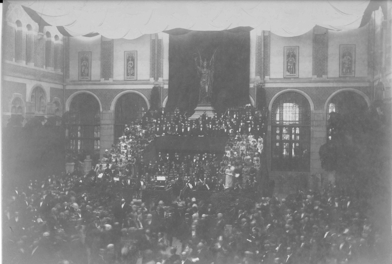 Foto van een redevoering in een van de zalen van het Rijksmuseum te Amsterdam.