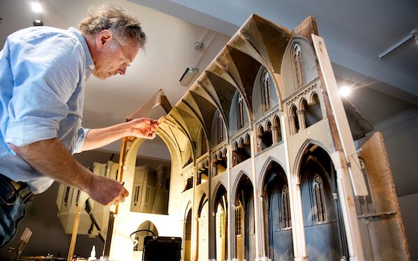 Foto van man die werkt aan restauratie van unieke kerkmaquettes