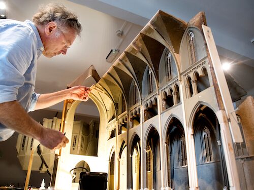 Foto van man die werkt aan restauratie van unieke kerkmaquettes
